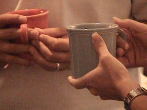 Two hands, each holding a coffee cup